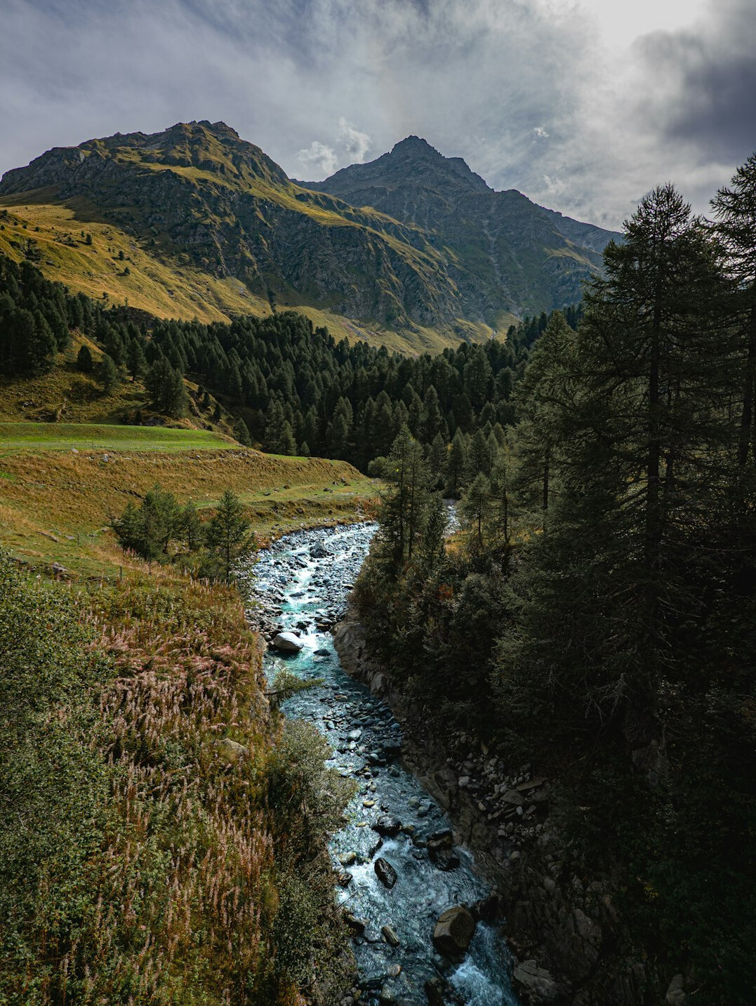 Journalist reviewing documents beside a Swiss alpine river valley